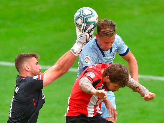 Atletico Marcos Llorente challenges Athletic Bilbao goalkeeper Unai Simon and Inigo Martinez during the La Liga clash.