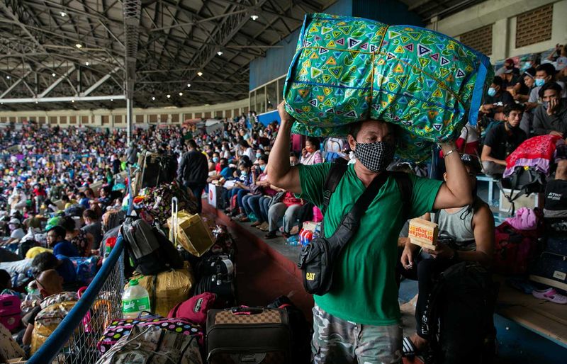A man carrying a bag of belongings walks inside the baseball stadium where thousands of stranded Filipinos due to the coronavirus disease (COVID-19) restrictions are crammed while waiting to be transported back to their provinces through a government transportation program, in Rizal Memorial Sports Complex, Manila, Philippines, July 25, 2020. 