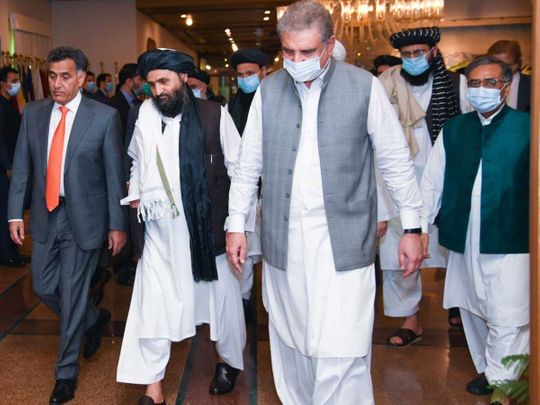 Pakistan's Foreign Minister Shah Mahmood Qureshi walks with Mullah Abdul Ghani Baradar 