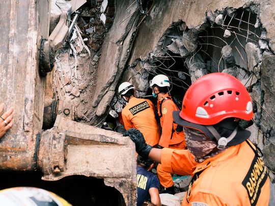 Rescuers search for victims at the ruin of a building damaged by an earthquake in Mamuju, West Sulawesi, on January 16, 2021.