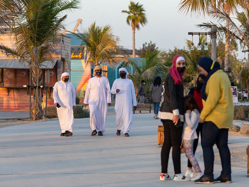 Pedestrians wearing protective masks walk through the La Mer development.