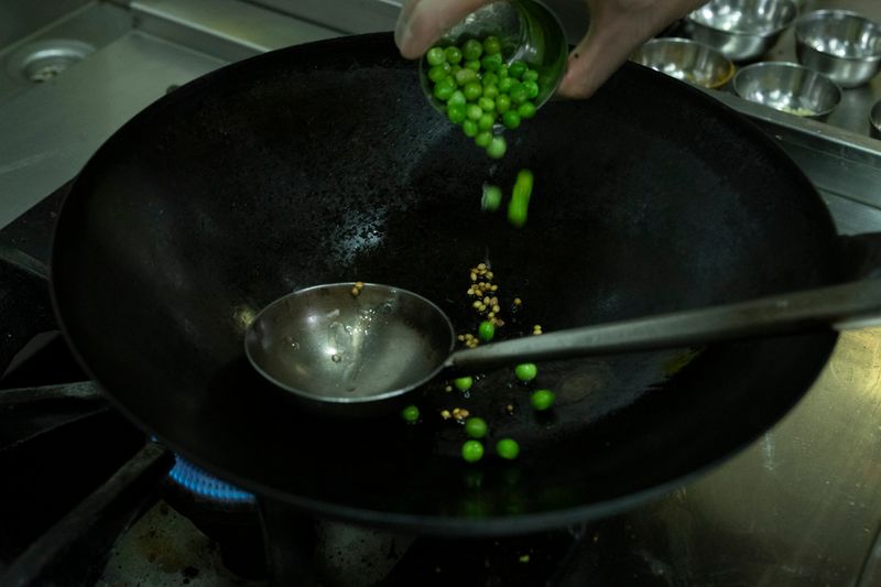 Add fresh green peas to the wok.