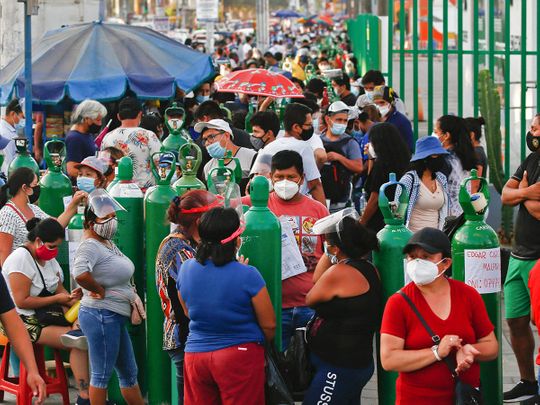 People wait to refill oxygen tanks in a queue of up to 200 people who camp outside a production plant, in San Juan de Lurigancho, Lima.  