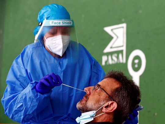A man has a swab sample taken for a COVID-19 antigen test, at a temporary site for massive testing at a fronton (court wall) in Pedrezuela, Spain. REUTERS