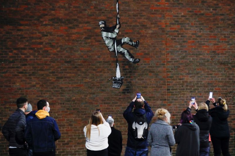 People take pictures of a suspected new mural by artist Banksy on a wall at HM Reading Prison in Reading, Britain, March 1, 2021. REUTERS/Matthew Childs