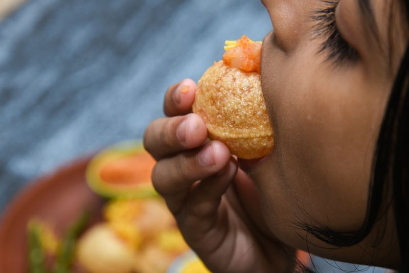 The only right way to eat a pani puri is to pop an entire puri, fillings and all, into your mouth.