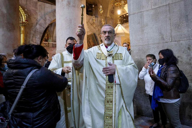 Latin Patriarch of Jerusalem Pierbattista Pizzaballa sprinkles holy water during a mass on Easter Sunday at the Church of the Holy Sepulchre in Jerusalem, on April 4, 2021.