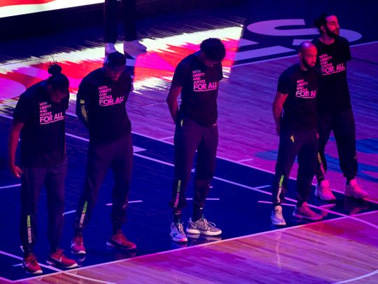 Members of the Minnesota Timberwolves, pictured, and the Brooklyn Nets wear T-shirts that read 