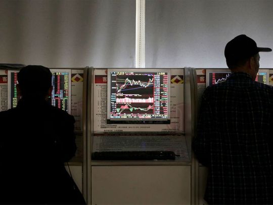 Investors check share prices at a brokerage office in Beijing