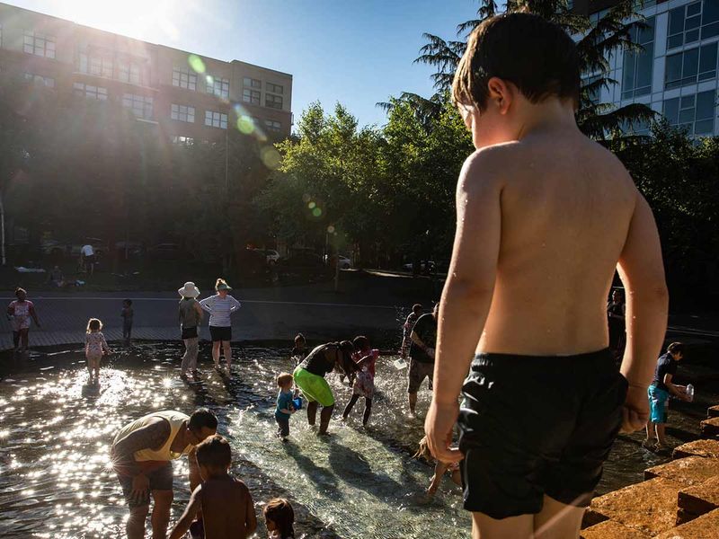 Children play in a water feature at a public park during a heatwave in Portland.