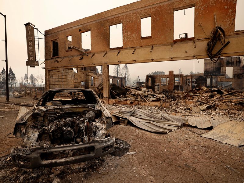 View of a burned out car and commercial building following the Dixie Fire, a wildfire that tore through the town of Greenville, California. 