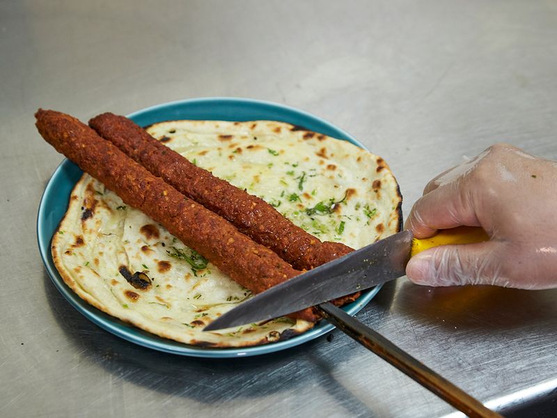 Remove seekh kebab on freshly baked naan bread 