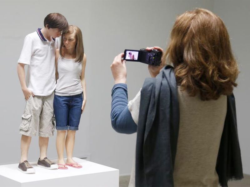A visitor takes a photo of a sculpture entitled 
