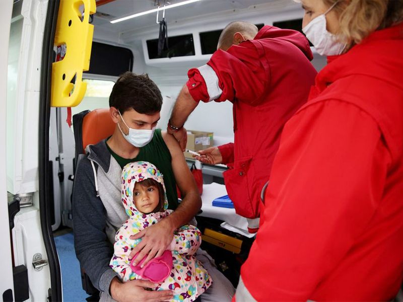 A man holds his daughter, as he receives a second dose of COVID-19 vaccine administered by a medical personnel from a mobile unit in the village of Krushovitsa, Bulgaria. 