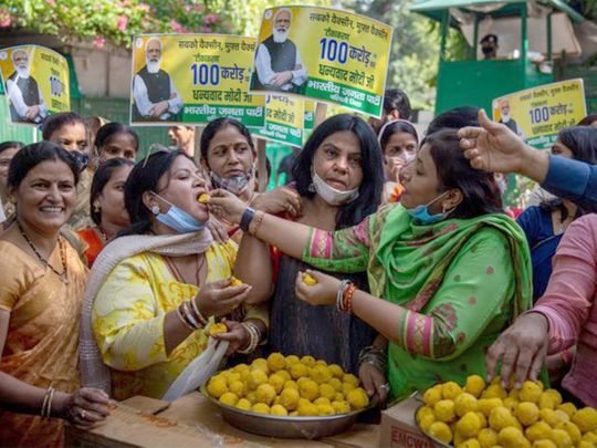 Members of India's ruling Bharatiya Janata Party (BJP) distribute sweets to celebrate 1 billion doses of COVID-19 vaccine in New Delhi. 