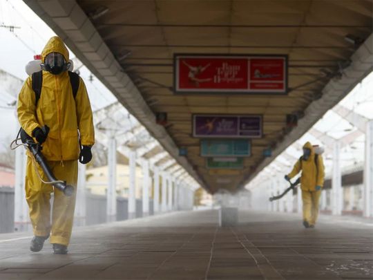 Des spécialistes portant des équipements de protection individuelle (EPI) vaporisent du désinfectant lors de la désinfection de la gare de Leningradsky à Moscou, le 19 octobre 2021. 