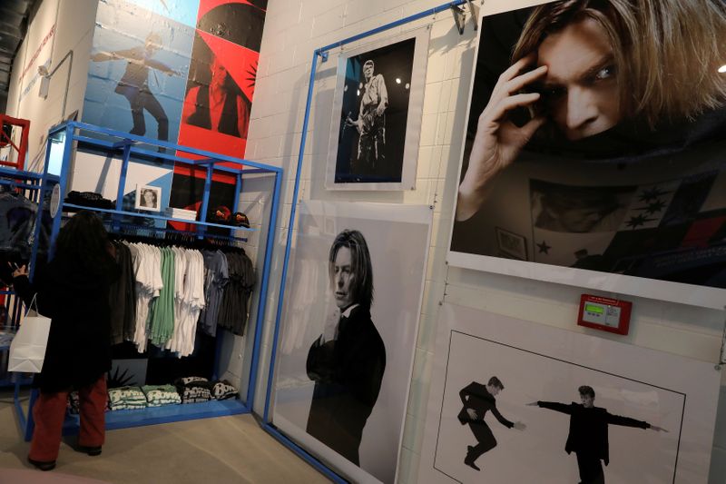 A woman shops next to images of the late rock and roll artist David Bowie inside 
