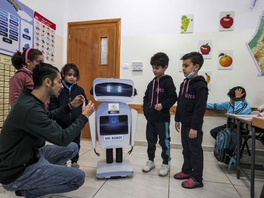 Palestinian teacher Hassan Al Razi gives a science class to students in his classroom while aided by a locally-made educational robot, at a private school in Gaza City on November 30, 2021. 