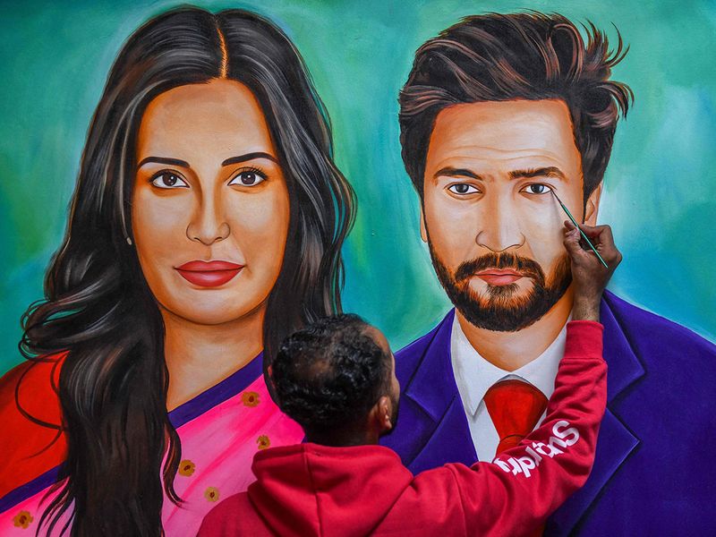An artist gives final touches to an oil painting of Indian Bollywood actors Vicky Kaushal and Katrina Kaif in his studio in Amritsar on December 9, 2021 which he plans to send as a wedding present to the couple.