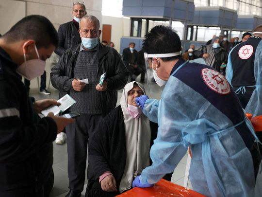 A Palestinian woman is tested for COVID-19 by an Israeli medic