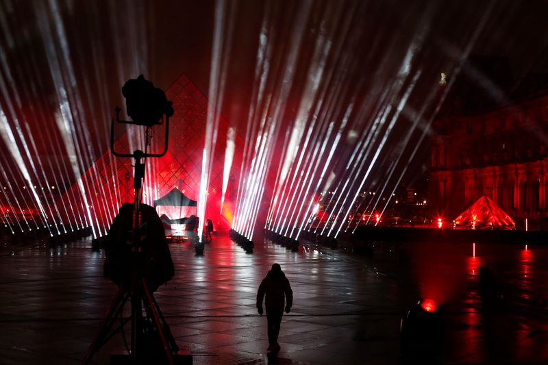 A technician walks in the courtyard of the Louvre museum during the rehearsal of a show by French DJ David Guetta, in Paris, Tuesday, Dec. 29, 2020. Superstar DJ David Guetta has, quite literally, been brought back to Earth by the coronavirus pandemic and says his music has benefitted as a result. Back in his native Paris to record a New Year's Eve show, the composer of ear-worm dance hits said he has produced 