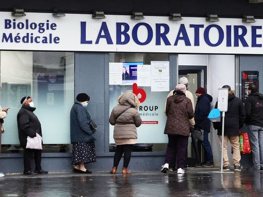 People queue for COVID-19 tests in front of a laboratory in Paris on Tuesday. 