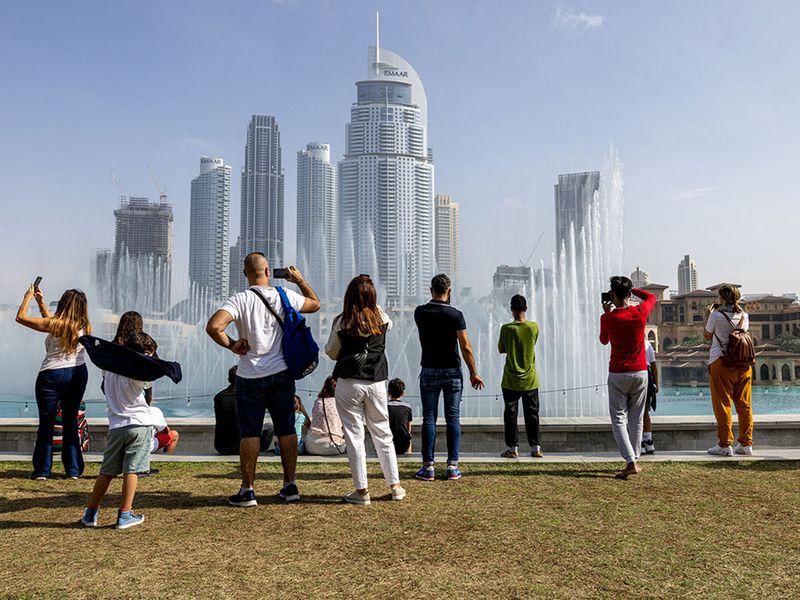 Tourists watch the water fountain display near the Burj Khalifa skyscraper, in Dubai, United Arab Emirates.