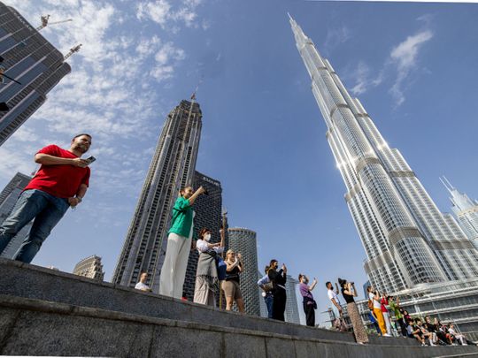 Tourists watch the water fountain display near the Burj Khalifa skyscraper, in Dubai, 