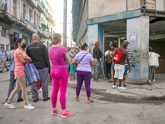 Cubans queue to by food outside a store in Havana