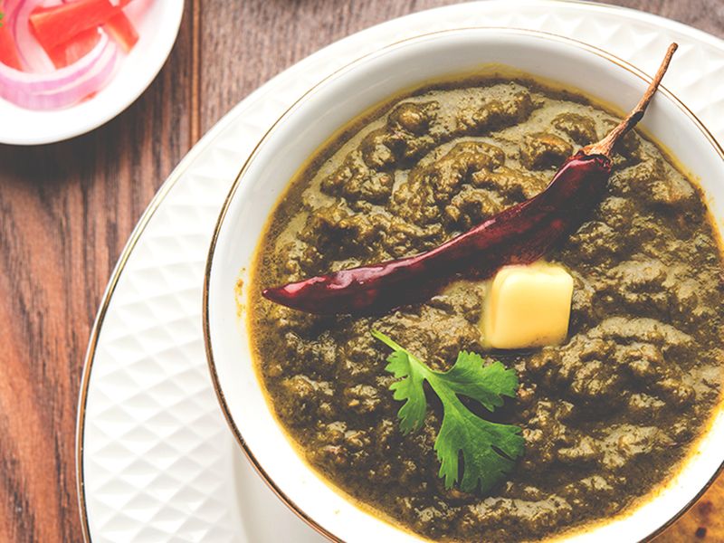a mix of green leaves such as spinach, mustard and radish, cooked in hearty spices and served with maize flour bread