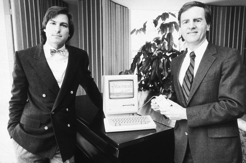 The ‘80s: Top Ten with Rob Lowe - (L-R) American businessman Steve Jobs (L), Chairman of Apple Computers, and John Sculley, Apple's president, pose with the new Macintosh personal computer.