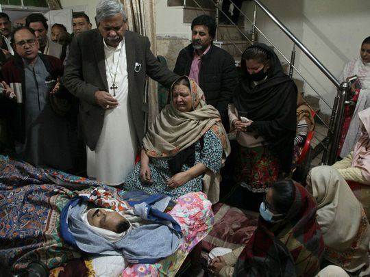 Relatives of Christian priest Father William Siraj, 75, who was killed by unknown gunmen, mourn next to his body at his home in Peshawar on January 30, 2022.