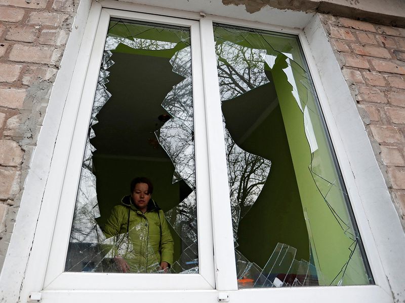 A woman is seen through the broken window of her house, which locals said was damaged by recent shelling, in the separatist-controlled town of Yasynuvata (Yasinovataya) in the Donetsk region, Ukraine. 