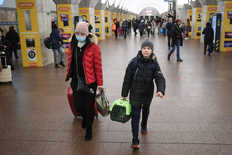 A youth walks with an enclosed cat carrier at a metro station in Kyiv.