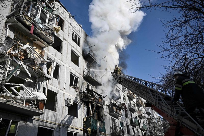 Firefighters work on a fire on a building after bombings on the eastern Ukraine town of Chuguiv.