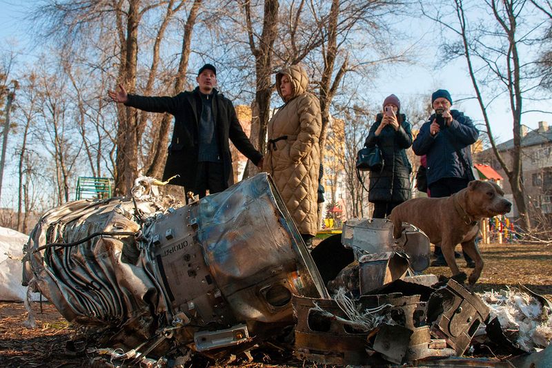 People stand next to fragments of military equipment on the street in the aftermath of an apparent Russian strike in Kharkiv in Kharkiv, Ukraine.