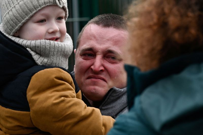 A man holding a child reacts as they arrive from Ukraine to Slovakia, after Russia launched a massive military operation against Ukraine, in Ubla, Slovakia,.