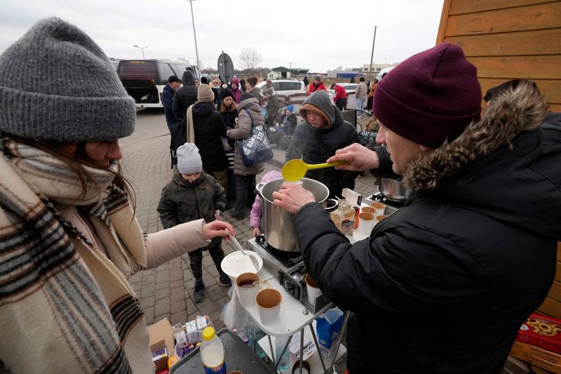 People fleeing the conflict from neighboring Ukraine, receive hot beverages at the border crossing in Medyka, southeastern Poland. 