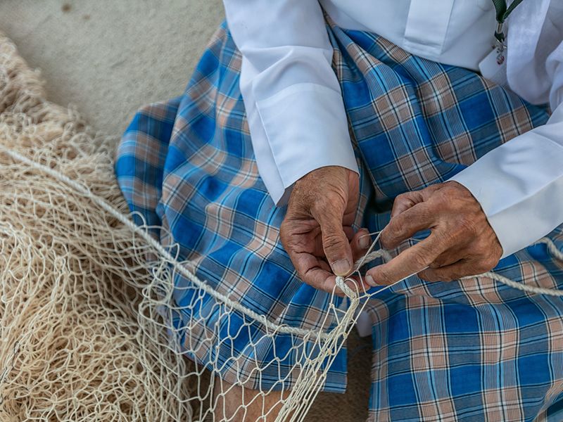 An Emirati making a traditional fishing net at Sheikh Zayed Festival 