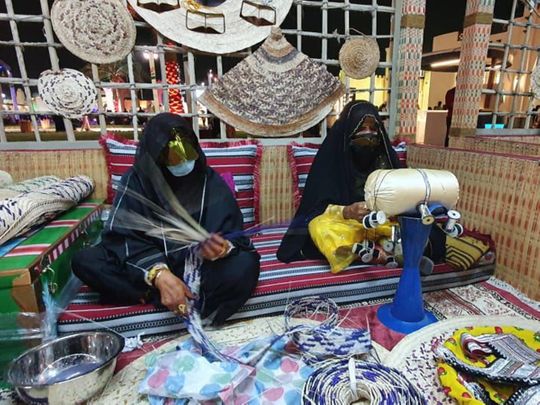 Umm Mohammad (right) displays 'talli' weaving to visitors to the Sheikh Zayed Festival. She is flanked by a friend who is weaving palm fronds.