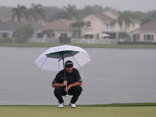 Shane Lowry looks at his shot as heavy rain falls on the 18 green during the final round of the Honda Classic 