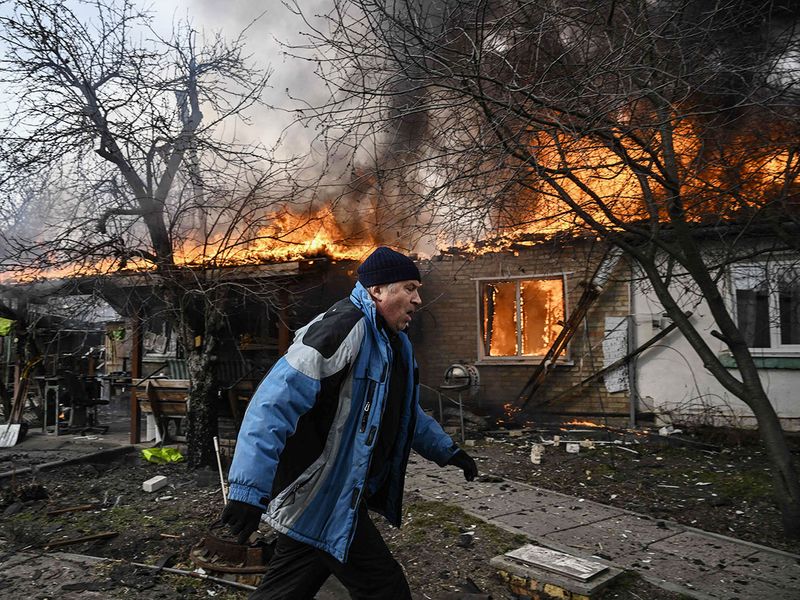 A man runs in front of a house burning after being shelled in the city of Irpin, outside Kyiv. 