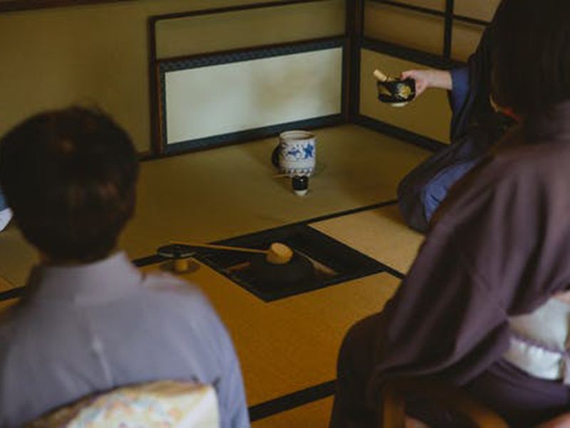 Guests and host sitting down on tatami mats for the tea ceremony. Image used for illustrative purpose only