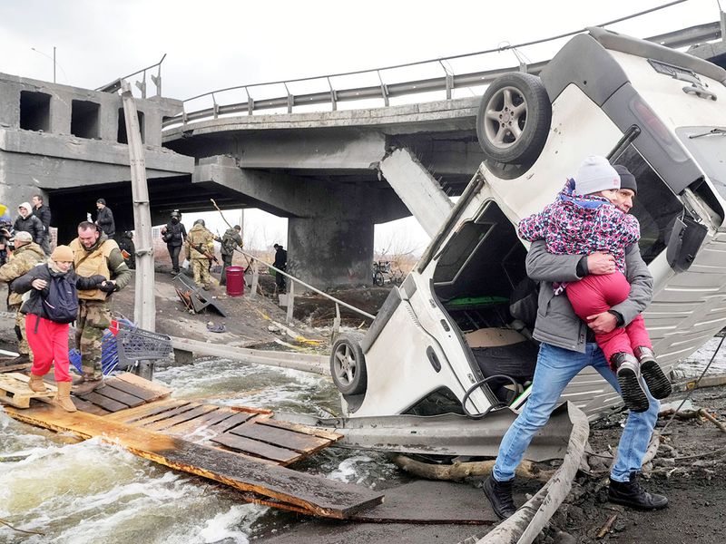 People cross an improvised path under a destroyed bridge while fleeing the town of Irpin close to Kyiv, Ukraine, Monday, March 7, 2022. 