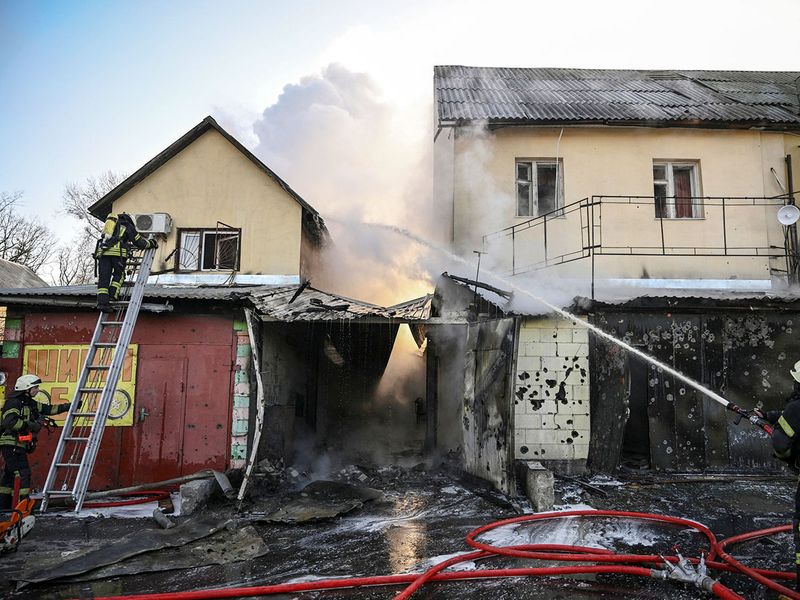 Firefighters extinguish a fire on a house after shelling in Kyiv on March 12, 2022.  