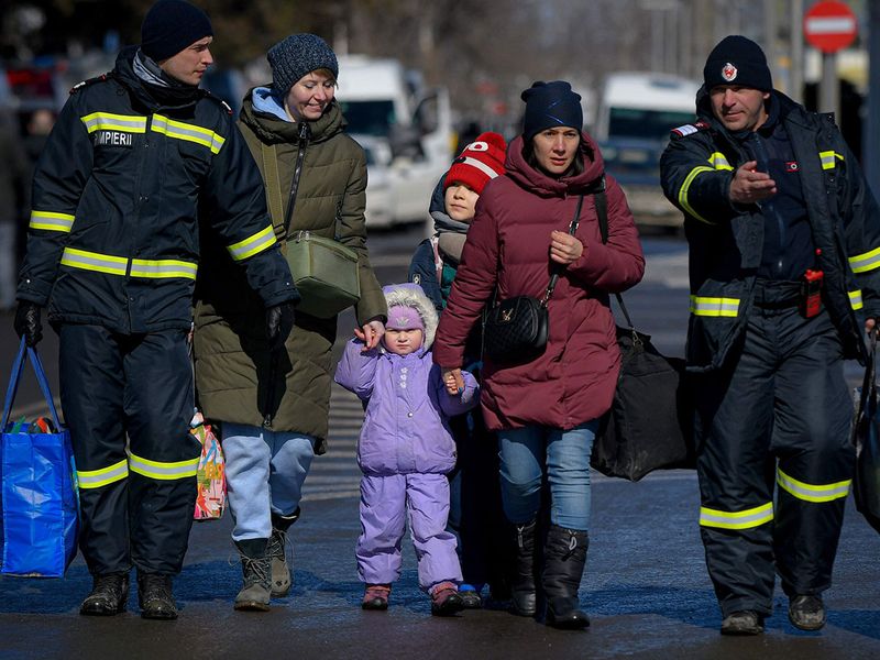 Romanian firefighters help refugees fleeing the conflict from neighbouring Ukraine after crossing the border, at the Romanian-Ukrainian border, in Siret, Romania. 
