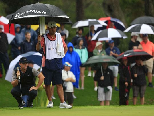 Rory McIlroy lines up a putt in pouring rain at the Players Championship 