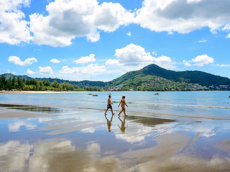 Tourists walk on a beach on the Thai island of Phuket.  