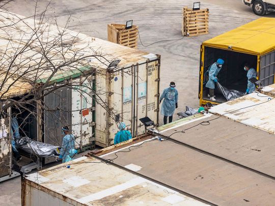 Workers move the bodies of deceased people from a truck into a refrigerated container at the Fu Shan Public Mortuary in Hong Kong on March 16, 2022.