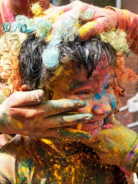 People smear colored powder on a boy as they celebrate Holi in Jammu, India